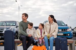 family waiting for a shuttle in Auckland Airport Park and ride car park