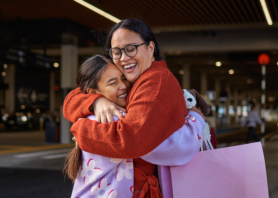 returning mother hugs daughter outside the transport hub at auckland airport because she booked short stay parking