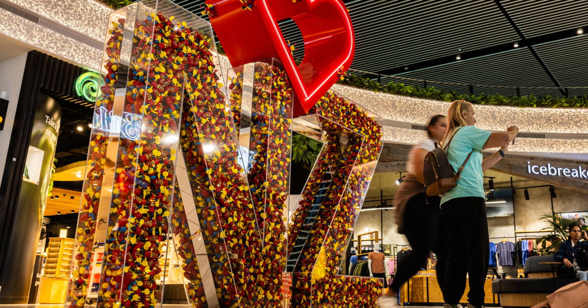 buzzy bee art installation featuring a clear plastic container shaped in the letters NZ and filled with buzzy bee figurines with a red love heart above it
